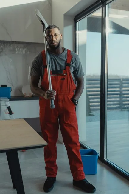 Young man engaged in household cleaning, wiping glass panels with a spray bottle.